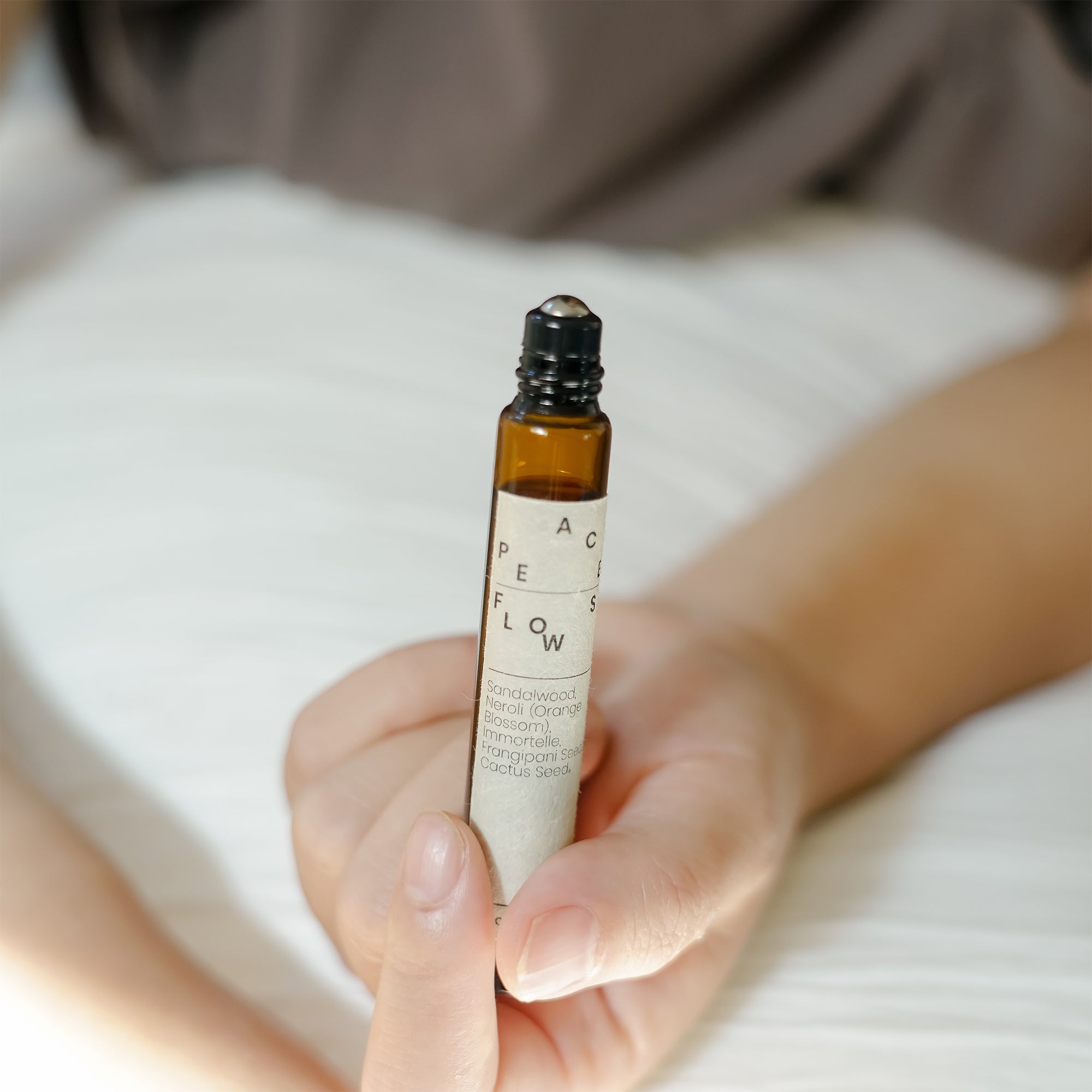 Hand holding a small brown glass bottle labeled &