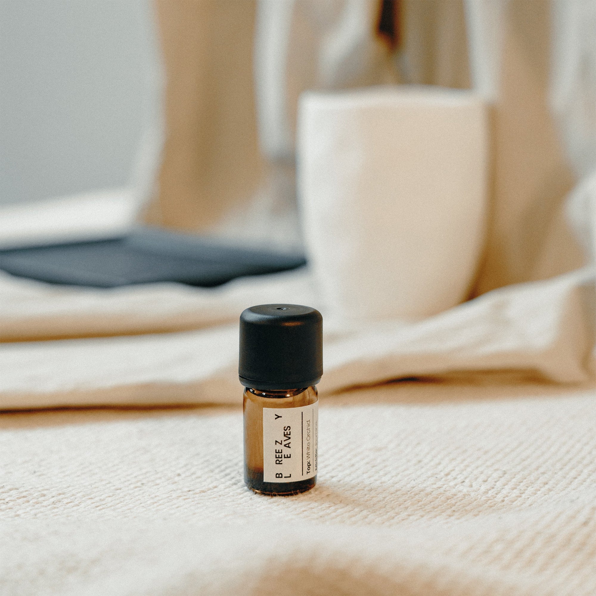 Small bottle of essential oil on a textured surface with a blurred background