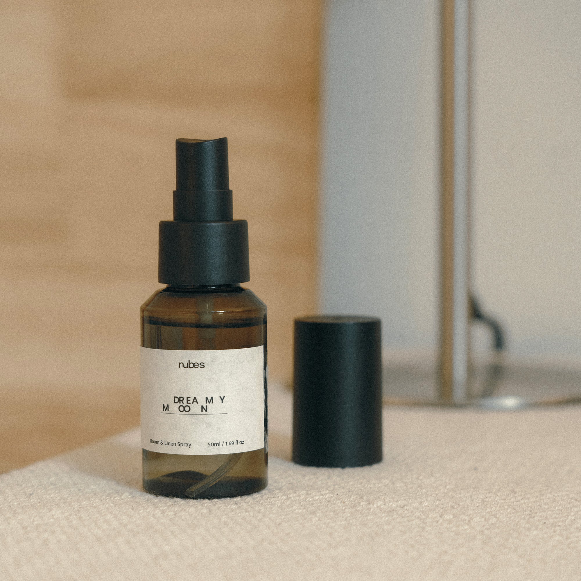 Nubes Dreamy Moon bottle with black cap on a textured surface