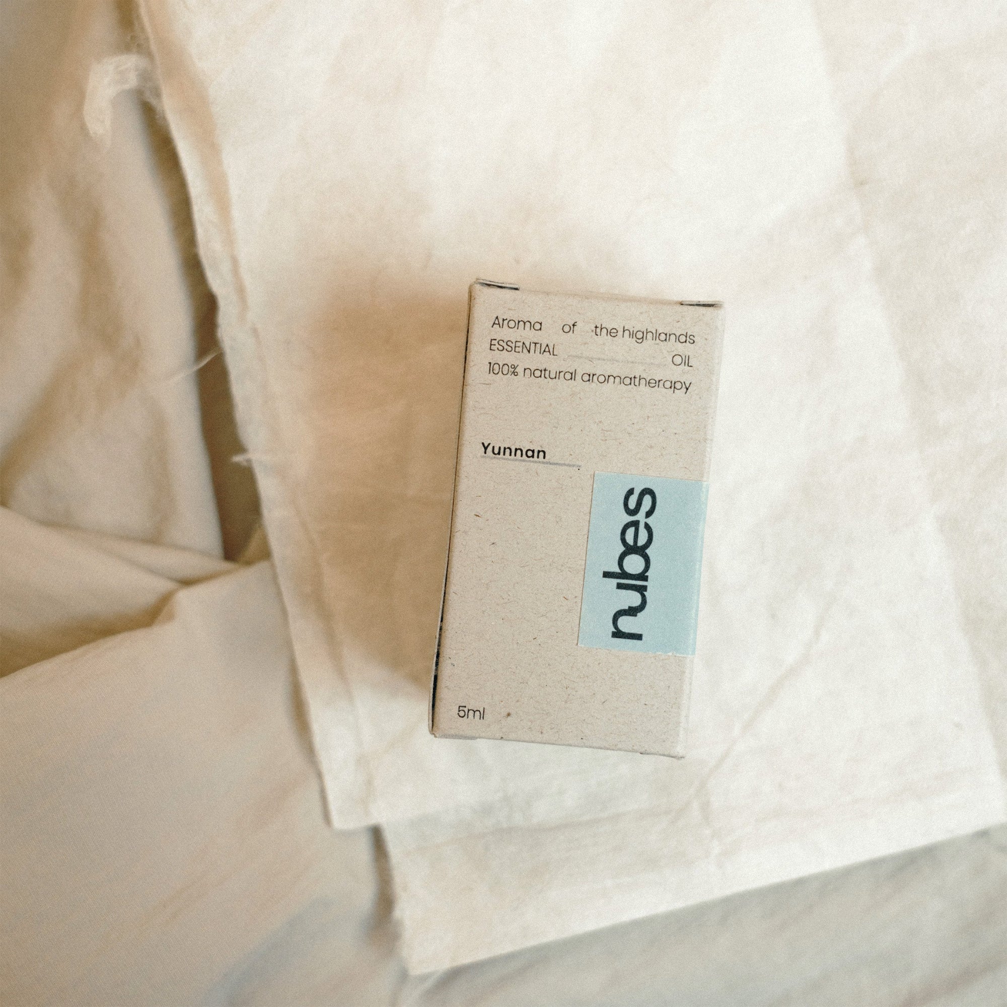 Nubes essential oil packaging on a textured beige fabric background