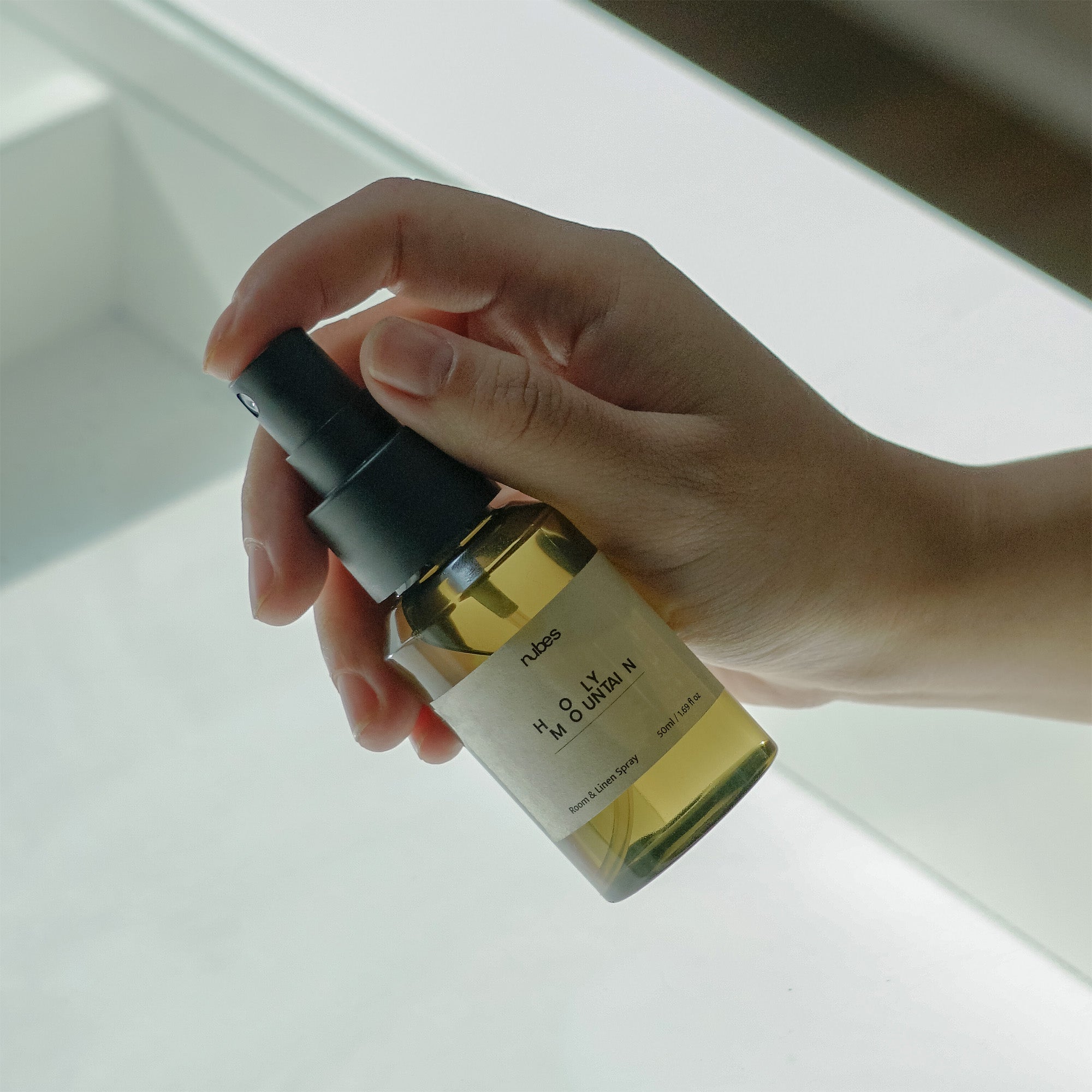 Hand holding a small bottle with a dropper against a neutral background