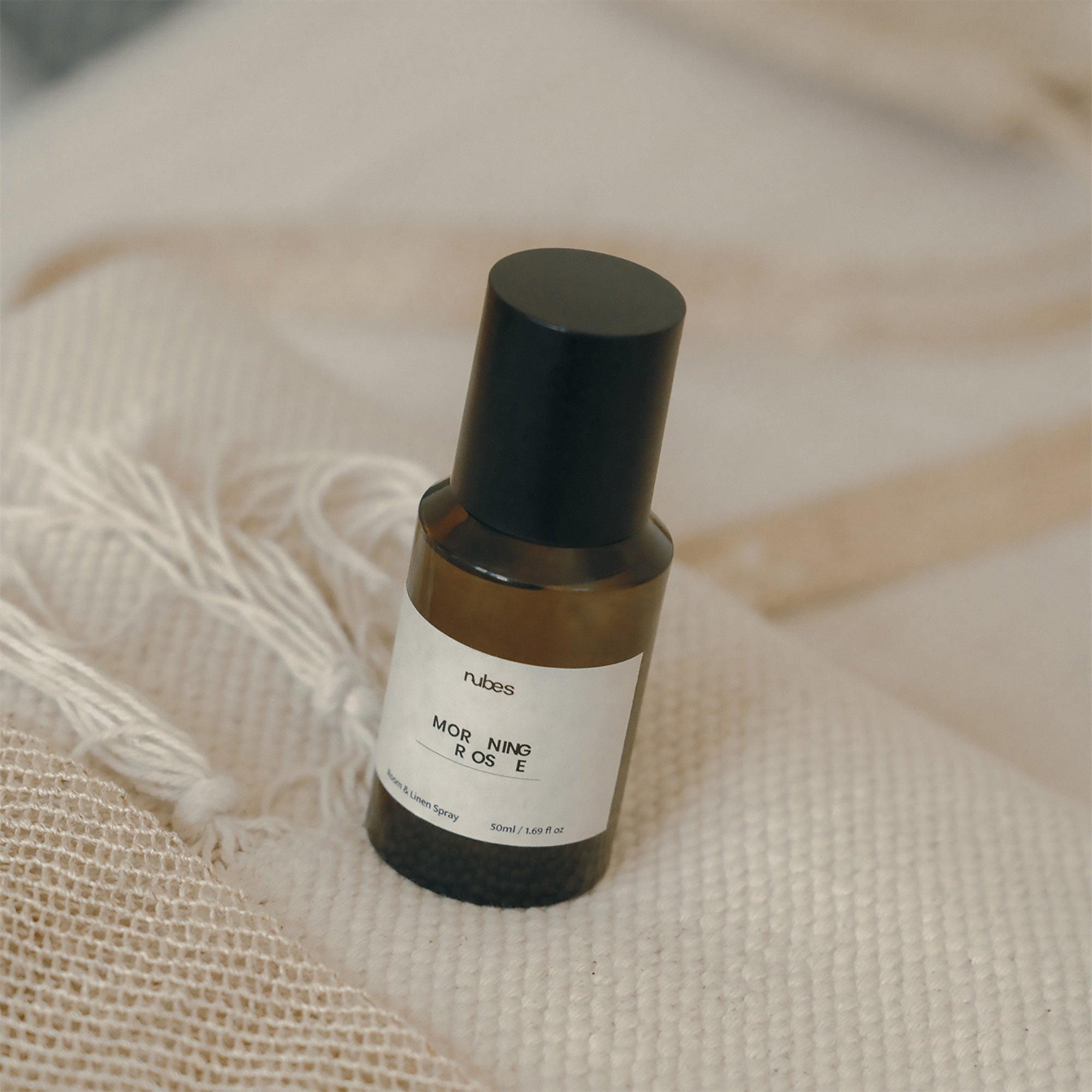 Spray bottle with a black cap and white label on a beige fabric background