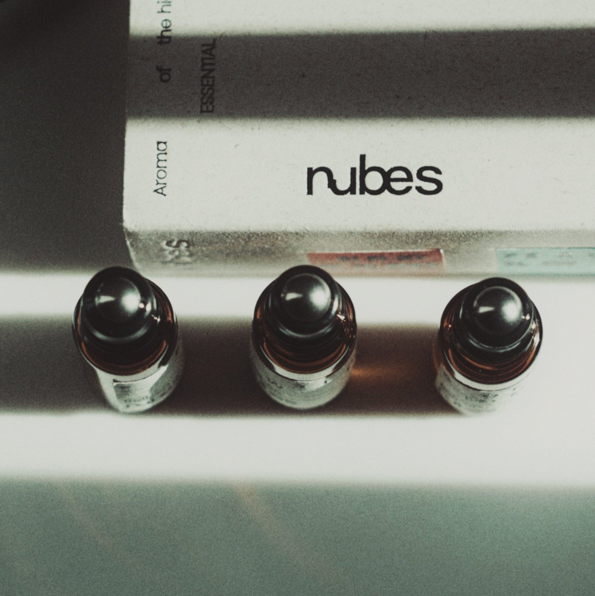 Close-up of Nubes roller bottles showing stainless steel applicator tips and minimalist label design.