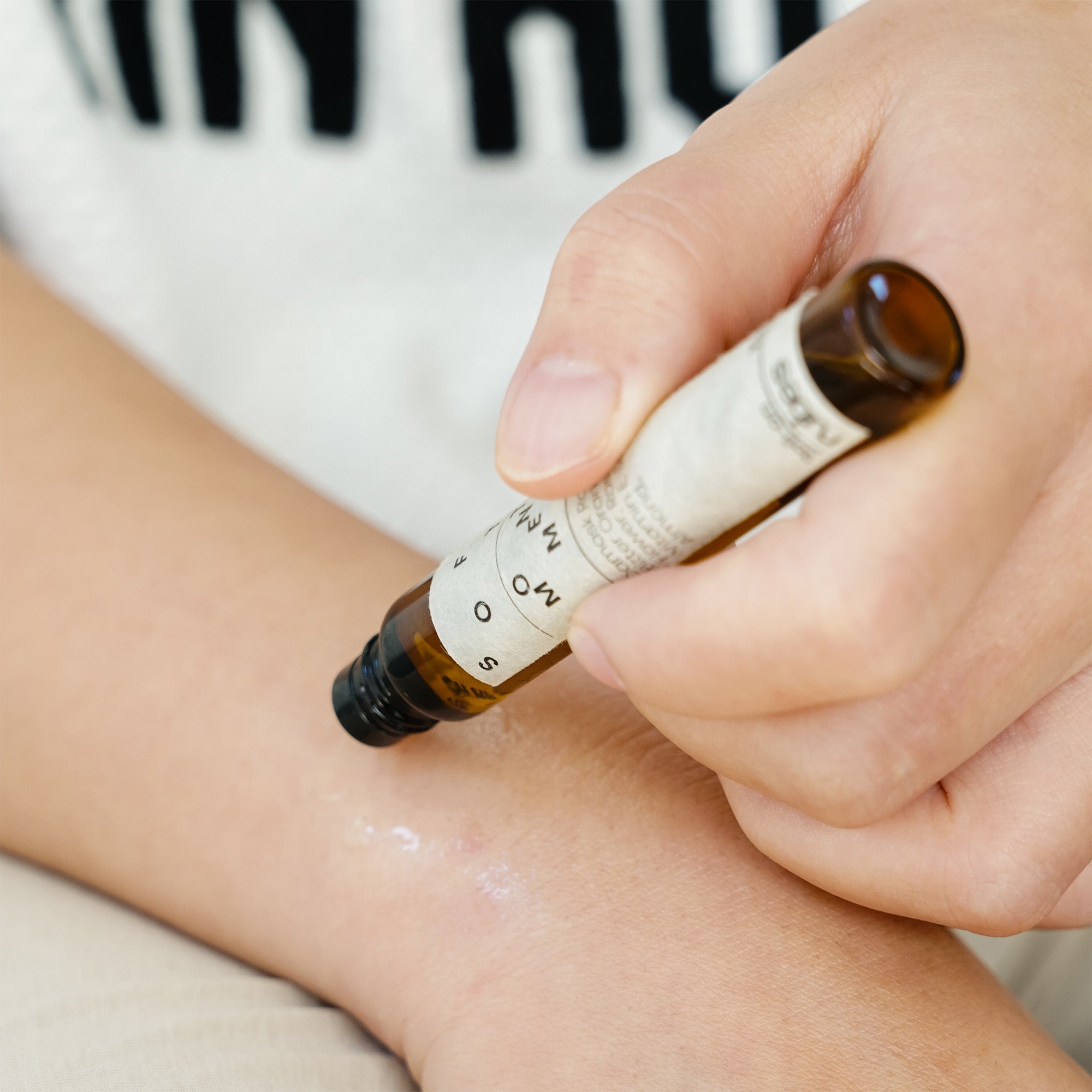 Small brown rollerball bottle with a white label on a white background