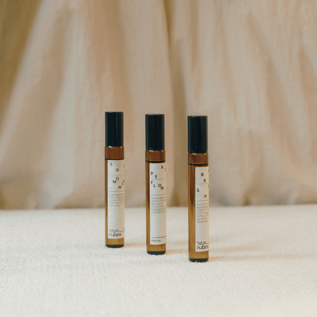 Three small roll on bottles with labels on a textured surface