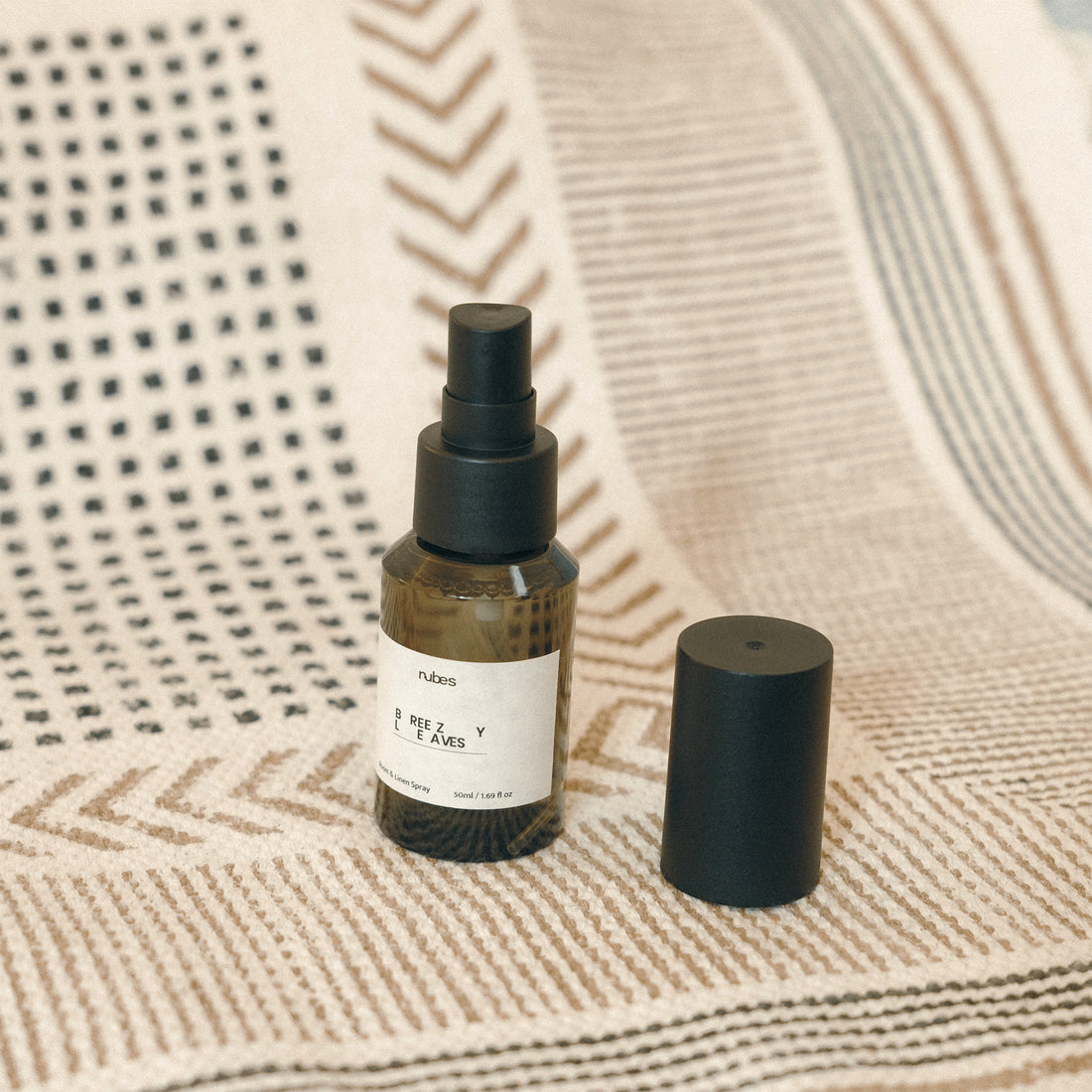 Spray bottle with black spray nozzle and white label on a textured beige surface