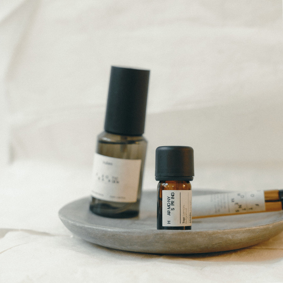 Three small bottles with black caps on a gray plate against a white background
