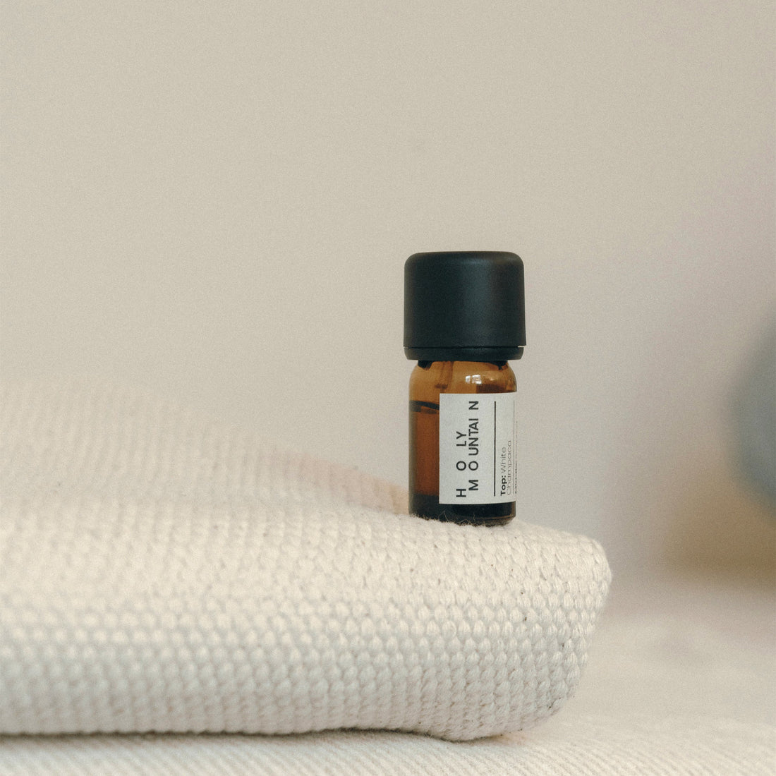 Small brown bottle with a black cap on a textured white surface