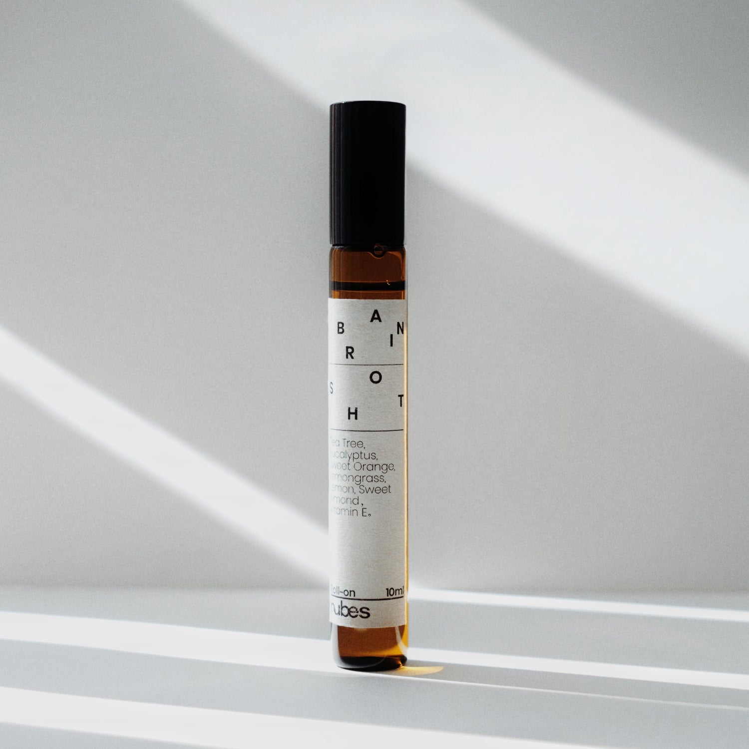 Nubes Brain Shot essential oil roll-on bottle standing upright in soft natural light, casting delicate shadows.