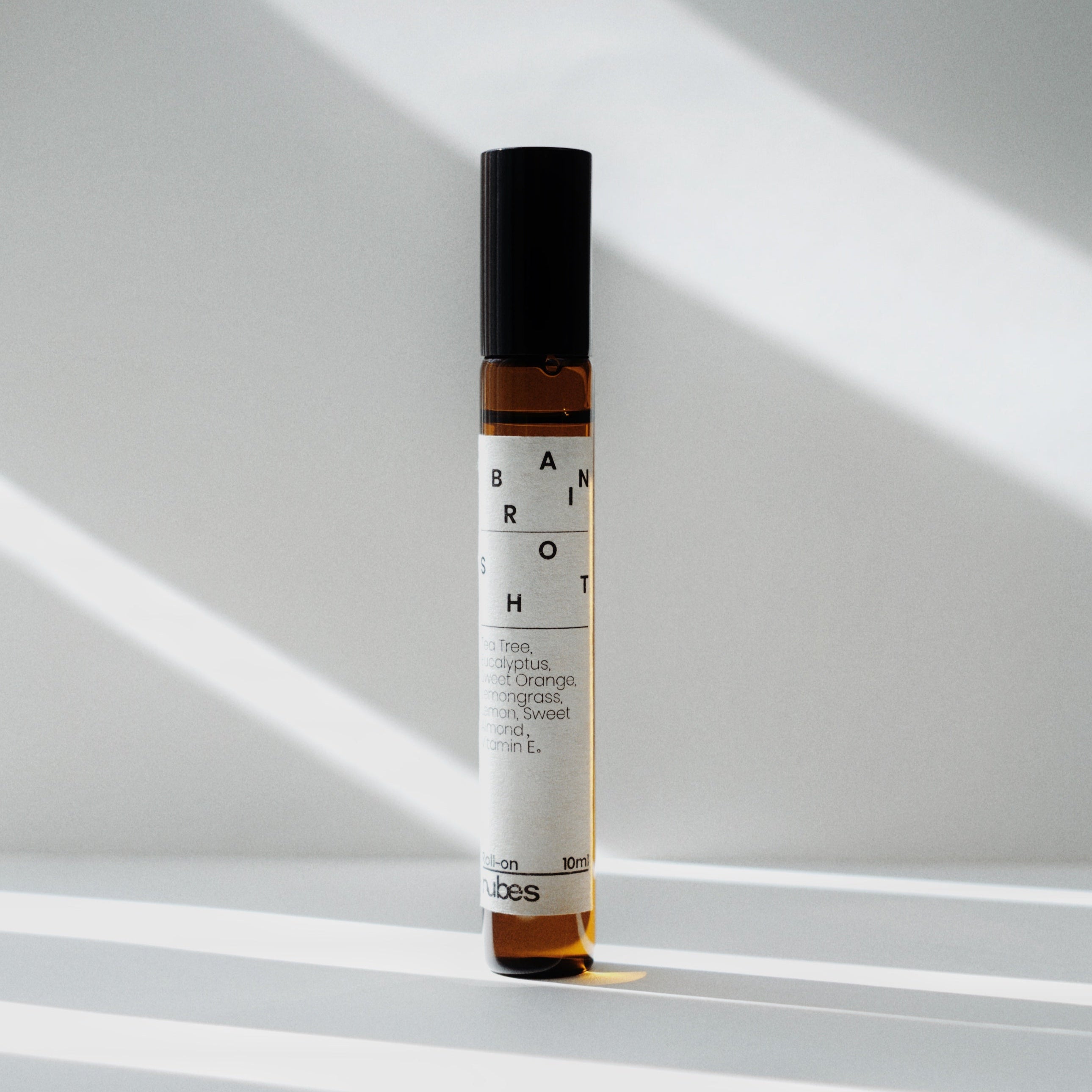 Nubes Brain Shot essential oil roll-on bottle standing upright in soft natural light, casting delicate shadows.