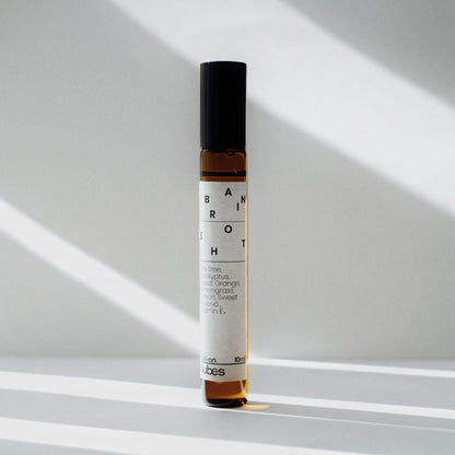 Nubes Brain Shot essential oil roll-on bottle standing upright in soft natural light, casting delicate shadows.