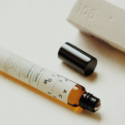 Nubes roll-on essential oil &quot;Peace Flows&quot; with its roller applicator exposed, accompanied by its minimalistic packaging.