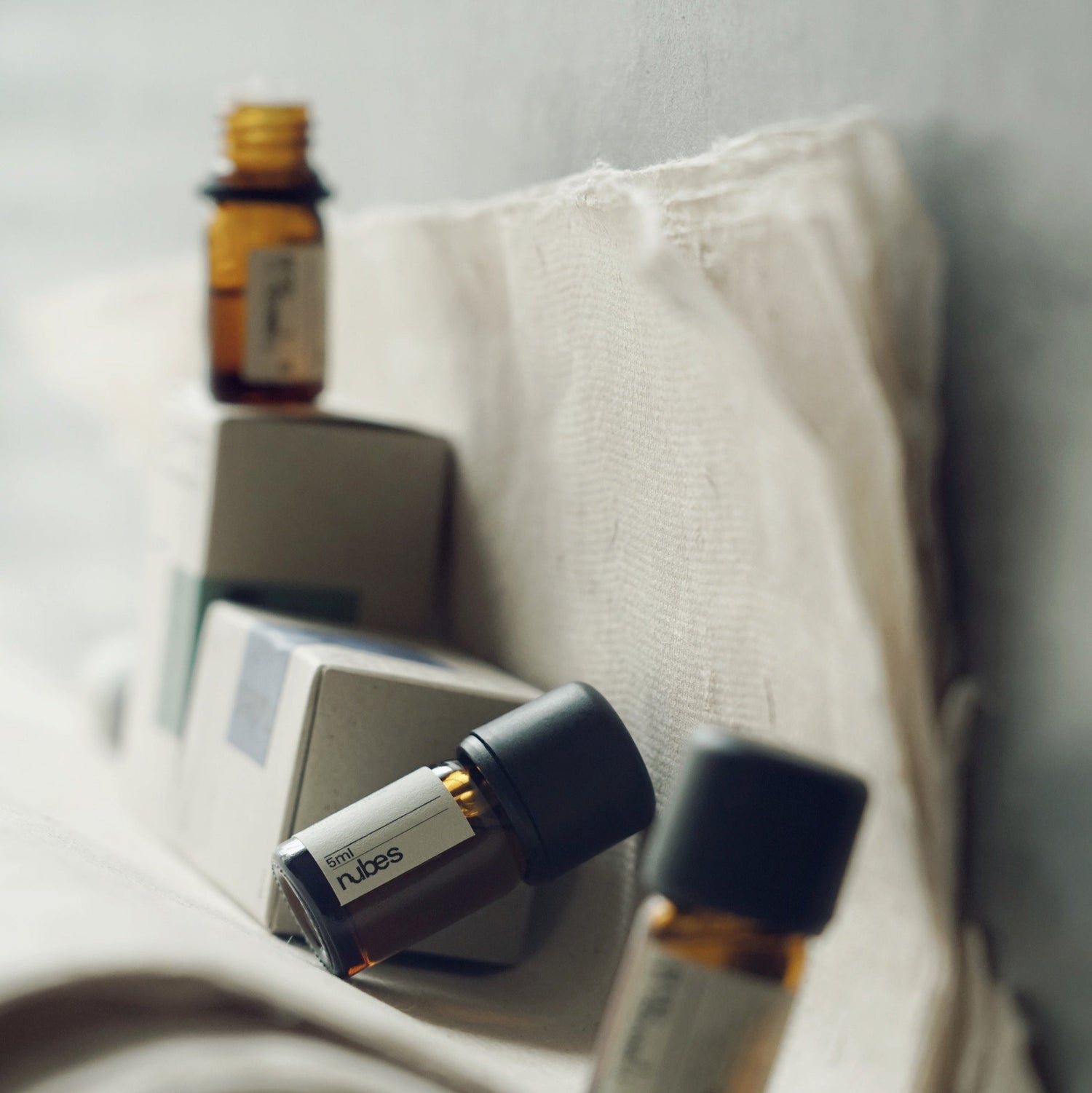 Amber glass bottle of Exotic Garden essential oil with a minimalist label and matte black cap. A 100% natural floral blend with ylang-ylang, jasmine, rose, and neroli. Light yet rich, creating a mysterious, elegant atmosphere. 5ml size.