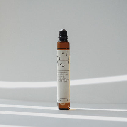 Nubes roll-on essential oil &quot;Peace Flows&quot; with an open applicator, bathed in soft striped light.