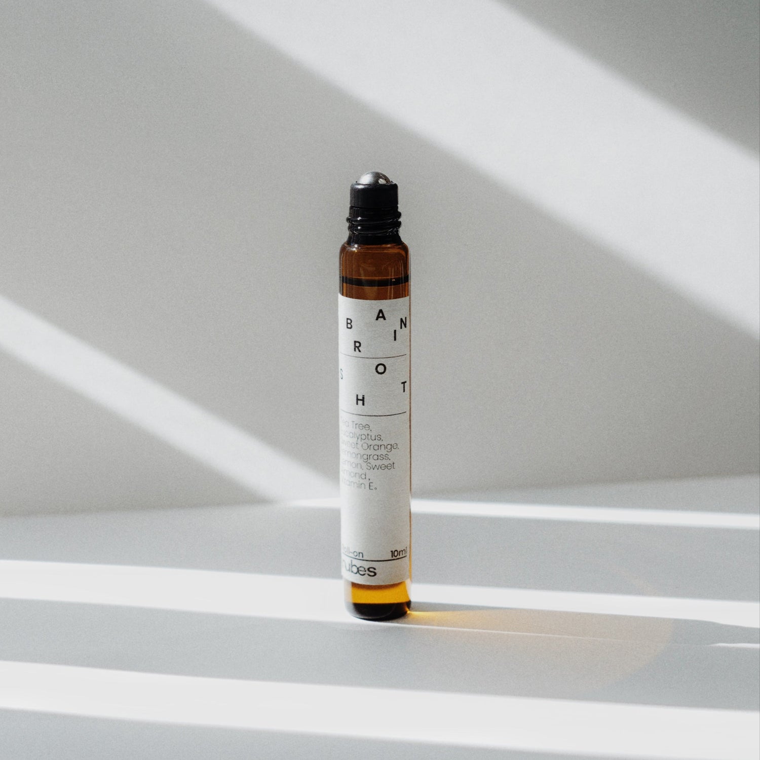 Nubes Brain Shot essential oil roll-on standing in soft sunlight, casting gentle shadows on a clean surface.