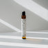 Nubes Brain Shot essential oil roll-on standing in soft sunlight, casting gentle shadows on a clean surface.