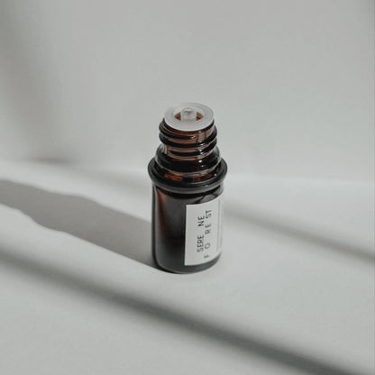 Nubes Serene Forest Essential Oil bottle with cap removed, bathed in soft shadows and natural light.