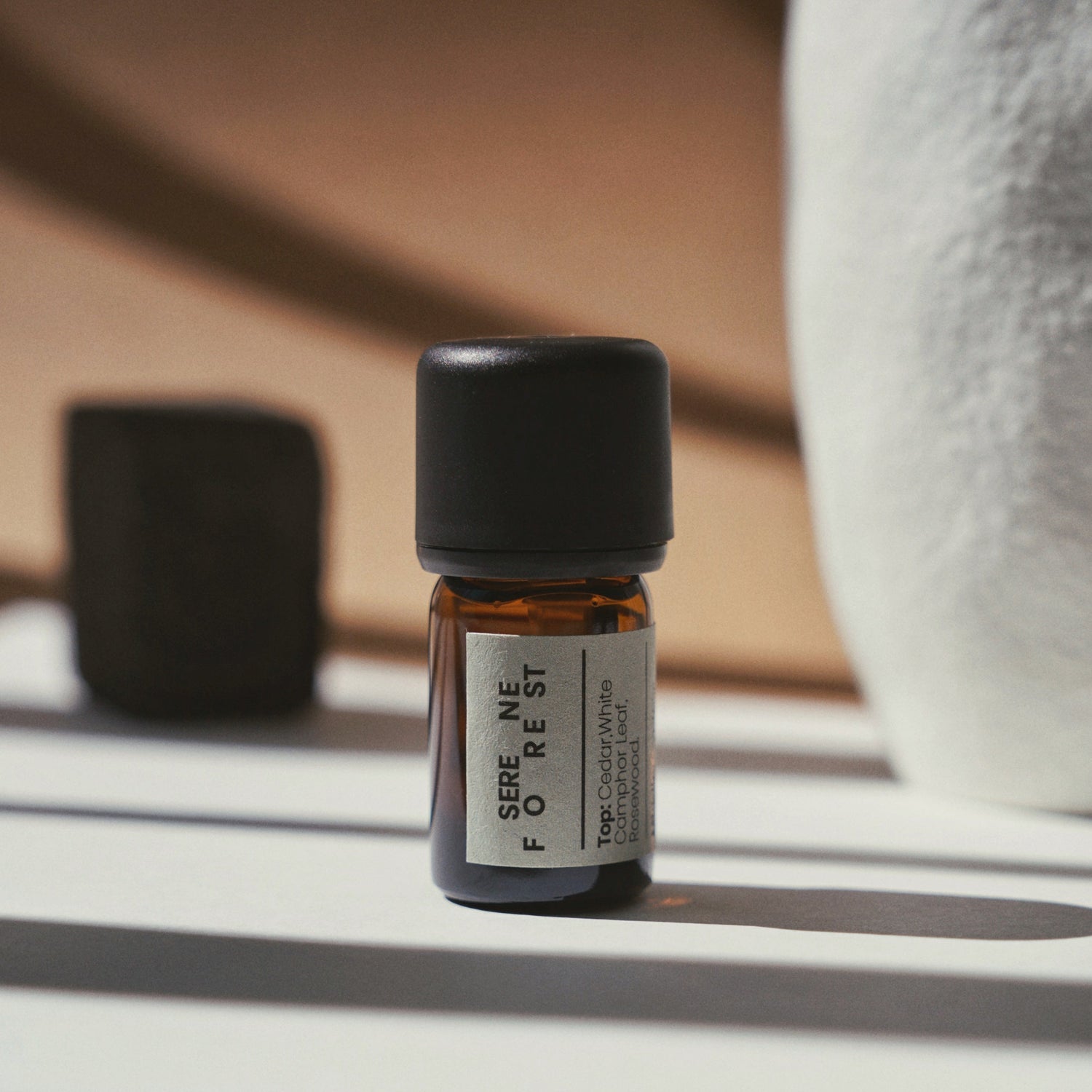 Nubes Serene Forest Essential Oil bottle in warm sunlight with soft shadows.