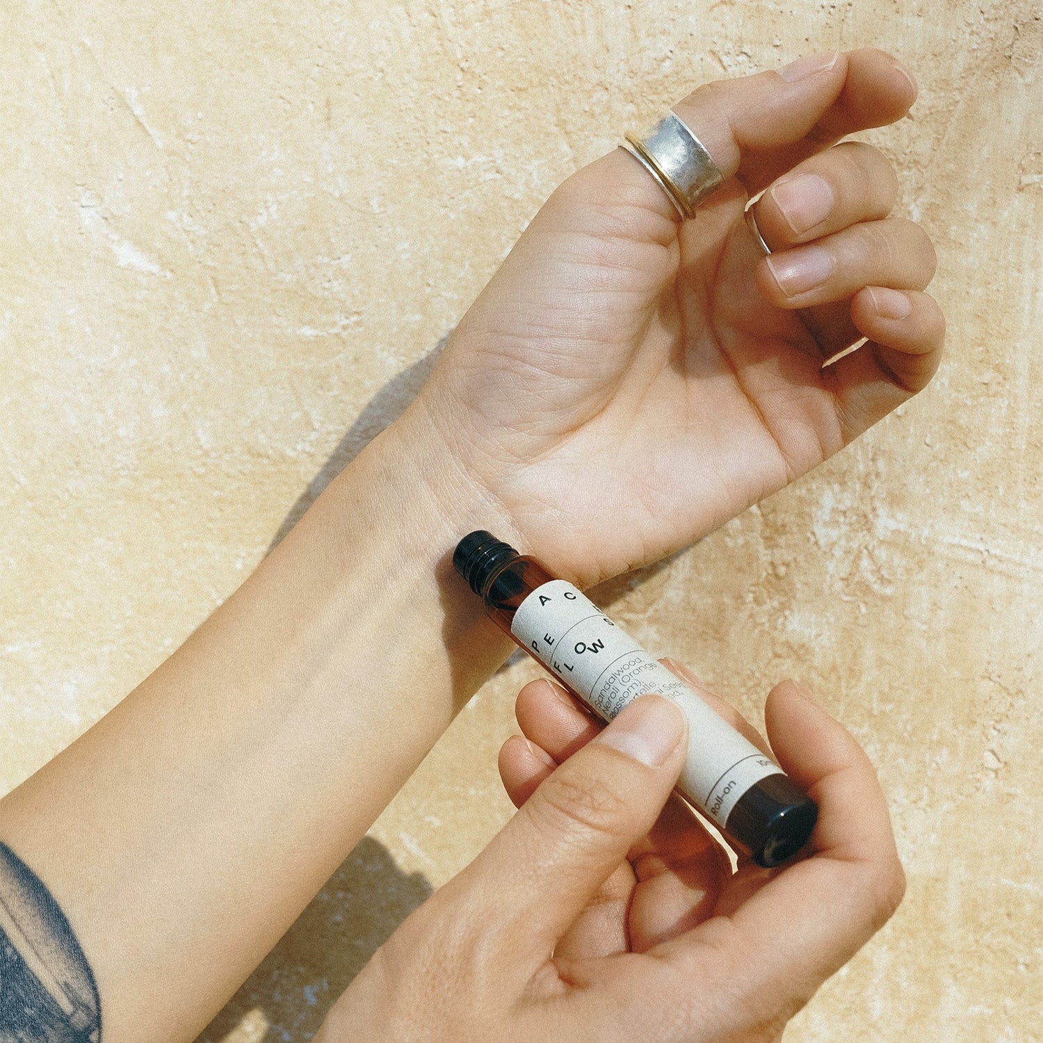 Person holding a small tube of roll on on a textured beige background