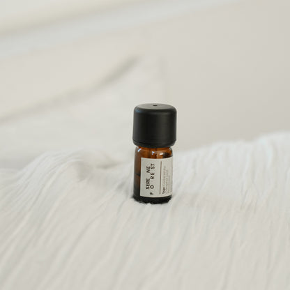 Small essential oil bottle with a black cap on a textured white surface