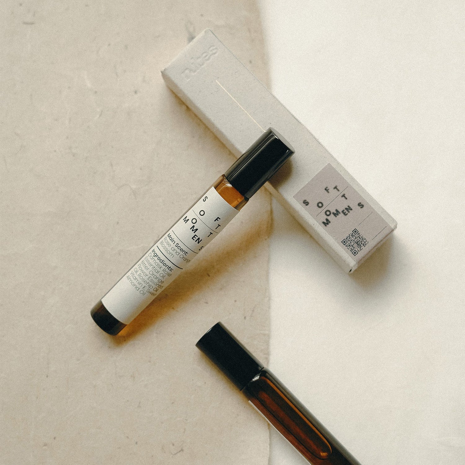 Two small bottles with black caps on a beige surface